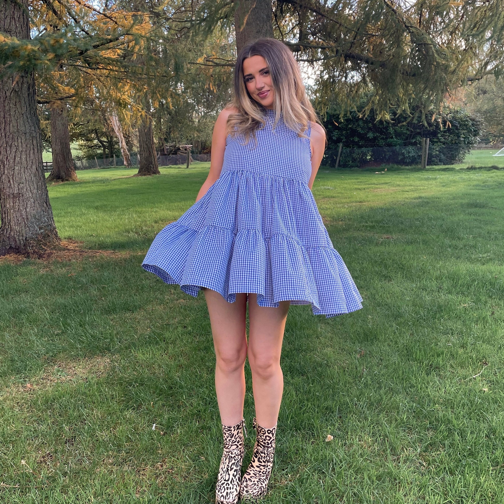 Woman in a blue checkered dress standing in a park