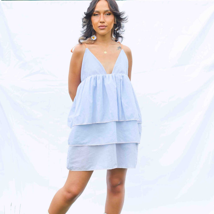 Fashion model wearing pale blue 3 tiered dress with orange elasticated straps at shoulder. 