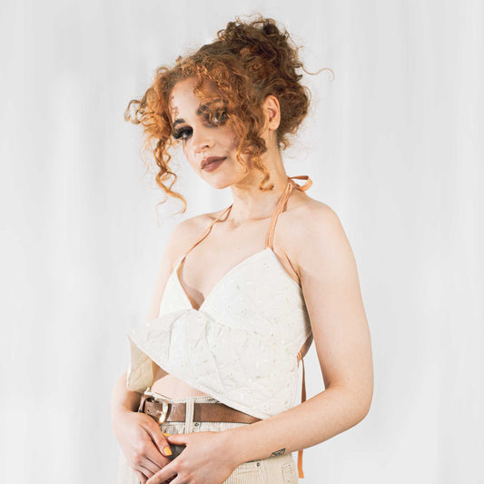 Fashion model wearing cream quilted backless bralette with orange elasticated straps at neck and back. 