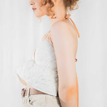 Load image into Gallery viewer, Fashion model wearing cream quilted backless bralette with orange elasticated straps at neck and back. 
